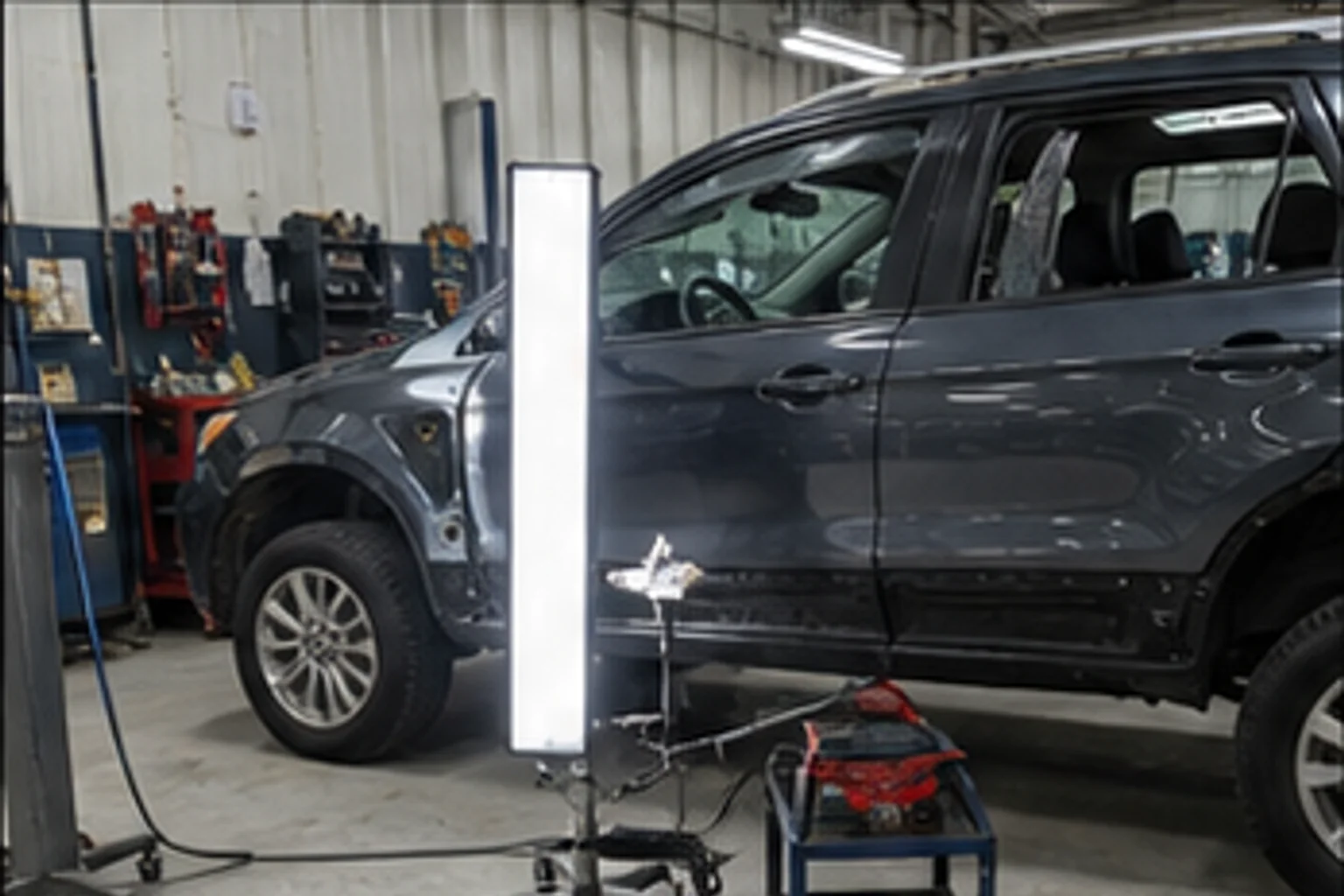 Technician inspecting repair work inside the Invisible Touch collision bay